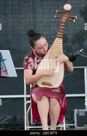 Ein schönes Mitglied des chinesischen Musikensembles von New York spielt die Pipa, ein traditionelles chinesisches Instrument. Auf dem Hong Kong Dragon Boat Fest Stockfoto