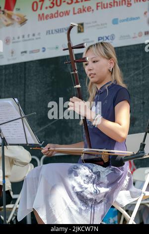 Ein schönes Mitglied des chinesischen Musikensembles von New York spielt das Erhu, ein traditionelles chinesisches Instrument. Auf dem Hong Kong Dragon Boat Fest, NYC Stockfoto