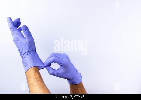 Zwei menschliche Hände in blauen Nitril-OP-Handschuhen, professionelle medizinische Sicherheit und Hygiene für Chirurgie und medizinische Untersuchung auf weißem Hintergrund. Lo Stockfoto