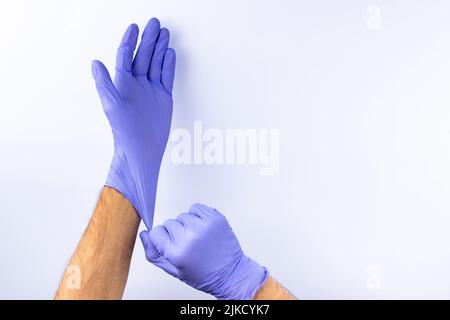 Zwei menschliche Hände in blauen Nitril-OP-Handschuhen, professionelle medizinische Sicherheit und Hygiene für Chirurgie und medizinische Untersuchung auf weißem Hintergrund. Lo Stockfoto