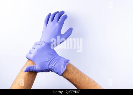 Zwei menschliche Hände in blauen Nitril-OP-Handschuhen, professionelle medizinische Sicherheit und Hygiene für Chirurgie und medizinische Untersuchung auf weißem Hintergrund. Lo Stockfoto