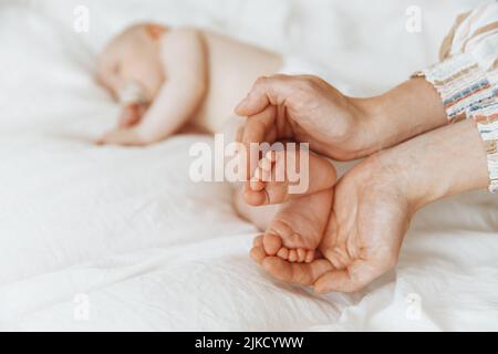 Die Beine der Kinder in den Händen der Mutter - die Form des Herzens. Die Beine eines Neugeborenen in den Armen einer Mutter haben die Form eines schönen Herzens Stockfoto