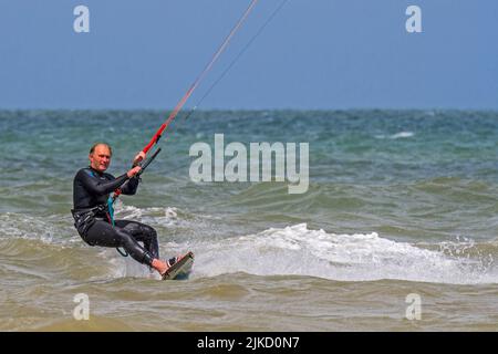 Kiteboarder / Kitesurfer trägt Neoprenanzug auf dem Twintip Board Kitesurfing an der Nordsee Stockfoto