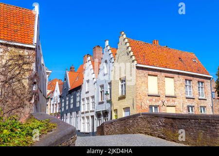 Brügge, Belgische Straße und Brücke, farbenfrohe traditionelle Häuser vor blauem Himmel in der beliebten belgischen Destination Brügge Stockfoto