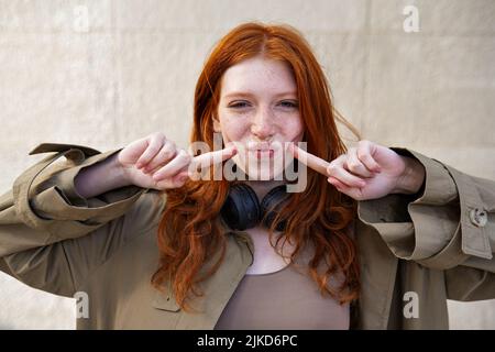 Glücklich lustig teen rothaarige Mädchen Blick auf Kamera auf Stadtmauer Hintergrund. Stockfoto