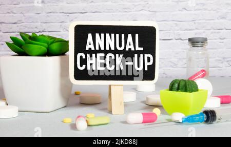 Stethoskop, Medizin, Kreidetafel und Blume mit Aufschrift jährliche Check-up auf einem Holztisch. Stockfoto