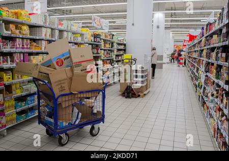 Moskau, Russland, 2019. September: Ein riesiger Lastenwagen mit einem Stapel leerer Kartons mit Waren im Supermarkt zwischen den Reihen von Lebensmitteln. Stockfoto