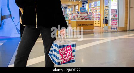 Moskau, Russland, Februar 2021: Eine Kundin hält in ihren Handpapiertaschen mit der Marke Bath and Body Works in einem blau-weißen Check und einem rosa Logo auf Stockfoto