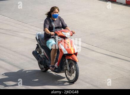 SAMUT PRAKAN, THAILAND, MAI 30 2022, Eine Frau mit Gesichtsmaske fährt ein Motorrad Stockfoto