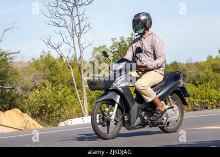 BANGKOK, THAILAND, JUNI 05 2022, Ein Mann mit Helm fährt ein Motorrad auf der Landstraße Stockfoto