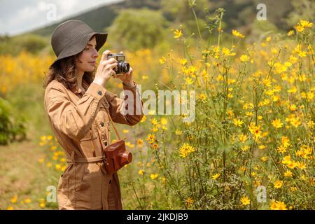 Lächelnde weibliche Touristen machen Foto von schönen Blumen in Afrika Stockfoto