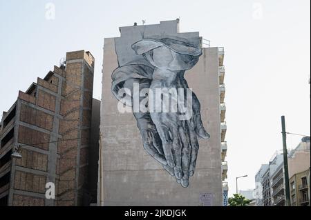 ATHEN, GRIECHENLAND - 14. MAI 2022: Zentrum von Athen Graffiti Street Art rund um Piräus. Gefaltete Handflächen Stockfoto