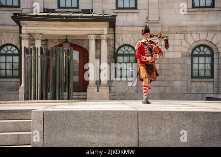 Montreal, Kanada - 13. Juli 2022: Schauspieler in schottischer Militäruniform vor dem Place Royale, der Dudelsäcke spielt Stockfoto