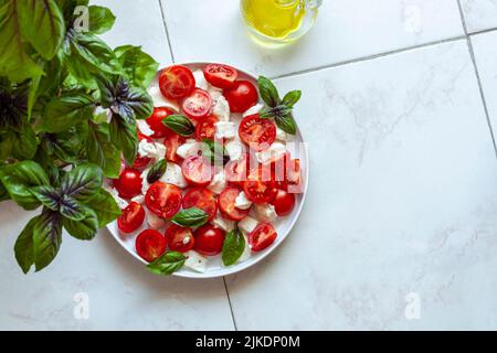 caprese Salat unter dem Hausgarten Basilikum Pflanze, Draufsicht, Copyspace Stockfoto