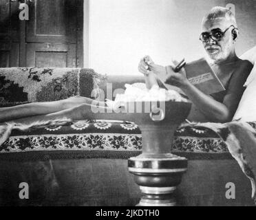 Schwarz-Weiß-Fotografie Porträt des indischen Weisen Sri Ramana Maharshi beim Lesen eines Buches, während er auf einer Couch liegt, Tiruvannamalai, Indien Stockfoto