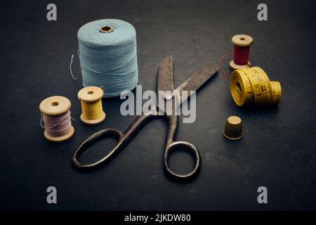 Alte Näh- und Schneiderutensilien, Schere, Faden, Maßband, Handhacken, Vintage-Toning, geringe Schärfentiefe Stockfoto