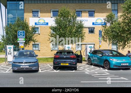 Elektrofahrzeuge, die an Ladestationen vor einem Days Inn-Hotel an der Wetherby-Schnellstraße A1(M) laden. Stockfoto