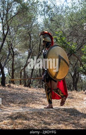 ATHEN, GRIECHENLAND - 14. MAI 2022: Der Künstler ist in ein Kostüm eines antiken griechischen Kriegers gekleidet, um in einem Park in der Nähe der Akropolis zu fotografieren. Sunny da Stockfoto