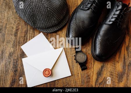 Herren-Outfits für Herrenbekleidung Set mit schwarzen klassischen Schuhen, Uhr und vintage grauen Hut isoliert auf Holzhintergrund. Draufsicht Stockfoto