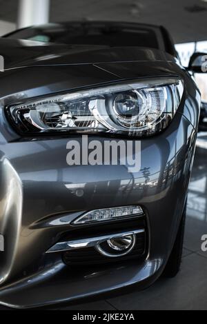 Nahaufnahme der modernen Scheinwerfer auf Luxus Silber Neuwagen im Automobil-Salon. Detail grau metallic Stoßstange Auto mit LED-Scheinwerfern. Außenansicht Auto c Stockfoto