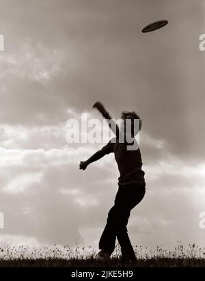 1970S ANONYMER SILHOUETTIERTER JUNGE WIRFT FRISBEE-SPIELSCHEIBE - B24951 HAR001 HARS S/W-ÜBERSICHT AKTIVITÄT GLÜCK KÖRPERLICHE FREIZEIT KRAFT SCHEIBE SILHOUETTIERTE AUFREGUNG ERHOLUNG TREND RICHTUNG FAD KONZEPTIONELLE FLEXIBILITÄT MUSKELN WIRFT FRISBEE ANONYME JUGENDLICHE PRE-TEEN PRE-TEEN JUNGE SCHWARZ-WEISSE SCHEIBE HAR001 NEUHEIT ALTMODISCH Stockfoto