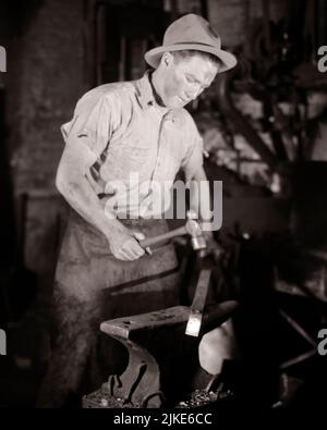 1930S MANN IN SCHMIEDE ARBEITET EIN STÜCK ERHITZTES METALL MIT EINEM KUGELHAMMER AUF EINEM AMBOSS - I840 HAR001 HARS STÄRKE KARRIERE ARBEIT BESCHÄFTIGUNG BERUFE KONZEPTIONELLE INFRASTRUKTUR ANGESTELLTER BEHEIZTER AMBOSS JUNGER ERWACHSENER MANN SCHWARZ-WEISS KAUKASISCHE ETHNIE HAR001 ARBEITET ALTMODISCH Stockfoto