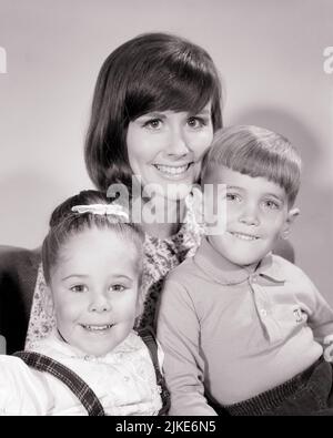 1960S PORTRAIT LÄCHELNDE BRÜNETTE MUTTER MIT ZWEI KINDERN JUNGE UND MÄDCHEN, DIE DIE KAMERA BETRACHTEN - J11901 HAR001 HARS ALTE MODE SCHWESTER 1 JUGENDLICHE JUNGE ERWACHSENE SÖHNE ERFREUT FAMILIEN FREUDE LIFESTYLE FRAUEN BRÜDER STUDIO SCHUSS GESUNDHEIT HEIM LEBEN KOPIEREN RAUM FREUNDSCHAFT DAMEN TÖCHTER PERSONEN MÄNNER VERTRAUEN SCHWESTERN B&W AUGENKONTAKT BRÜNETTE GLÜCK KOPF UND SCHULTERN FRÖHLICH UND LÄCHELT VERBINDUNG FREUDIGES WACHSTUM MÜTTER ZWEISAMKEIT SCHWARZ-WEISS KAUKASISCHE ETHNIE HAR001 ALTMODISCH Stockfoto