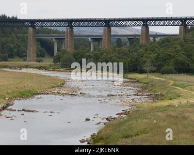 Blick auf den Fluss Findhorn, der unter dem Eisenbahnviadukt und der Straßenbrücke A9 in der Nähe von Tomatin, Inverness, vorbeiführt. Stockfoto