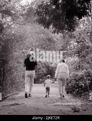 1960S RÜCKANSICHT DER FAMILIE, DIE AUF DEM WALDPARKWEG SPAZIERENGEHT VATER TRÄGT TOCHTER HUCKEPACK UND MUTTER HÄLT KLEINKIND SON’S HAND - J13212 HAR001 HARS DAD FOUR AUSÜBUNG MAMA NOSTALGISCH AKTIV PAAR 4 SUBURBANEN MÜTTER ALTE ZEIT NOSTALGIE BRUDER ALTE MODE SCHWESTER 1 FITNESS JUGENDLICH GESUND FRIEDEN SÖHNE FAMILIEN LEBENSSTIL ZUFRIEDENHEIT FRAUEN VERHEIRATET BRÜDER LÄNDLICHEN EHEGATTEN EHEMÄNNER GESUNDHEIT KOPIEREN RAUM FREUNDSCHAFT DURCHGEHENDE DAMEN TÖCHTER PERSONEN INSPIRATION MÄNNER GELASSENHEIT GESCHWISTER SCHWESTERN VÄTER B&W PARTNER AKTIVITÄT PFAD GLÜCK KÖRPERLICHE FREIZEIT KRAFT UND VÄTER GESCHWISTER IN DER RÜCKANSICHT Stockfoto