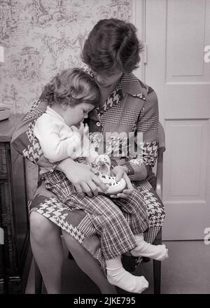 1970S MUTTER TRÖSTET KLEINKIND MÄDCHEN SITZT IN IHREM SCHOSS UNSICHER ÜBER DAS ANZIEHEN IHRER SCHUHE - J13704 HAR001 HARS JUNG ERWACHSENE STARK ABSTRAKT FAMILIEN LIFESTYLE FRAUEN HEIM LEBEN KOPIEREN RAUM FREUNDSCHAFT HALBJÄHRIGE DAMEN TÖCHTER PERSONEN FÜRSORGLICH S&W LAP MÜTTERLICHE AUTORITÄT MUTTER UND TOCHTER VERBINDUNG MUTTERSCHAFT PERSÖNLICHE BINDUNG ZUNEIGUNG ZUSAMMENARBEIT EMOTION JUGENDLICHE MÜTTER ZWEISAMKEIT JUNGE ERWACHSENE FRAU SCHWARZ-WEISS KAUKASISCH ETHNIZITÄT HAR001 ALTMODISCH UNSICHER Stockfoto