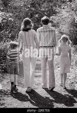 1970S VIERKÖPFIGE FAMILIE VON HINTEN, DIE EINEN SCHATTEN WIRFT, DER AUF EINEM BEWALDETEN PFAD DIE HÄNDE HÄLT - J14169 HAR001 HARS DOWN EHEMANN VATER VIER AUSÜBUNG MUTTER SCHATTEN KLEIDUNG NOSTALGISCH AKTIV PAAR 4 MÜTTER ALT ZEIT NOSTALGIE ALTE MODE SCHWESTER 1 FITNESS JUGENDLICHE STIL GESUND URLAUB SÖHNE FAMILIEN FREUDE LIFESTYLE FEIER FRAUEN VERHEIRATET LÄNDLICHEN EHEGATTEN EHEMÄNNER NATUR KOPIEREN RAUM IN VOLLER LÄNGE DAMEN TÖCHTER PERSONEN FÜRSORGLICH MÄNNER GELASSENHEIT SCHWESTERN VÄTER B&W PARTNER SOMMER ZEIT WEG AKTIVITÄT PFAD GLÜCK KÖRPERLICHE ABENTEUER KRAFT REISE KURZURLAUB VÄTER ERHOLUNG HÄLT HÄNDE RÜCKANSICHT URLAUB Stockfoto