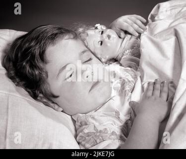 1960S BRÜNETTE MÄDCHEN FRIEDLICH SCHLAFEN IM BETT MIT ARM UMWICKELT HALTEN IHRE PUPPE - J1637 HAR001 HARS ENTSPANNUNG SCHWARZ UND WEISS KAUKASISCHEN ETHNIE HAR001 ALTMODISCH Stockfoto