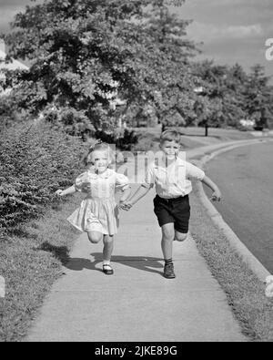 1940S 1950S JUNGE BRUDER UND MÄDCHEN SCHWESTER HALTEN HÄNDE LAUFEN DIE VORSTADTSTRASSE IN RICHTUNG BLICK AUF DIE KAMERA - J619 HAR001 HARS FITNESS JUGENDSTIL GESUNDE TEAMARBEIT ATHLET FREUDE LIFESTYLE GESCHWINDIGKEIT FEIER FRAUEN BRÜDER GESUNDHEIT HEIM LEBEN LEICHTATHLETIK KOPIEREN RAUM FREUNDSCHAFT FULL-LENGTH PERSONEN INSPIRATION FÜRSORGLICHE MÄNNER RISKIEREN SPORTLICHE GESCHWISTER ZU VERTRAUEN SCHWESTERN B&W AUGENKONTAKT AKTIVITÄT GLÜCK KÖRPERLICHES WOHLBEFINDEN HOHER WINKEL KRAFT UND AUFREGUNG ERHOLUNG GESCHWISTER VERBINDUNG KONZEPTIONELLE ATHLETEN FLEXIBILITÄT MUSKELN STYLISCHE KURZE HOSEN KOOPERATION WACHSTUM JUGENDLICHE ZWEISAMKEIT Stockfoto