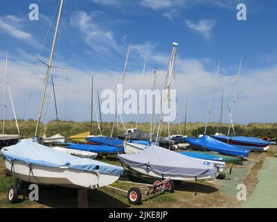 Boote, die an den Sanddünen am Strand von Findhorn an einem perfekten Sommertag mit nur wispigen Wolken in einem tiefblauen Himmel festgemacht sind. Stockfoto