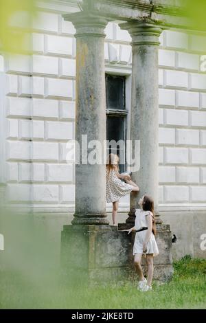 Zwei kleine europäische Mädchen spielen in der Nähe der Säulen Stockfoto