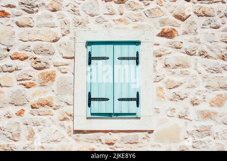 Hellblaue Fensterläden in einer Steinwand geschlossen. Stockfoto