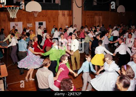 1950S 1960'S GRUPPE VON JUNGEN UND ALTEN MÄNNERN UND FRAUEN WESTERN SQUARE TANZEN IN EINEM GYMNASIUM MIT SPASS - KD2633 SHE001 HARS FARBE SENIOREN TÄNZER ALTE ZEIT BESCHÄFTIGT NOSTALGIE GUTE ALTE MODE PLATZ FITNESS MIT VIELEN STIL WILLKOMMEN KOMMUNIKATION GESUNDES GLEICHGEWICHT TEAMWORK FIT FREUDE LIFESTYLE GESCHWINDIGKEIT FEIER ÄLTERE FRAUEN LÄNDLICH ERWACHSEN GESUNDHEIT HORIZONTAL KOPIEREN RAUM FREUNDSCHAFT GANZKÖRPERFRAUEN KÖRPERLICHE FITNESS PERSONEN INSPIRATION ERWACHSENE FÜRSORGLICHE MÄNNER WESTERN ENTERTAINMENT CONFIDENCE WEITWINKEL-AKTIVITÄT GLÜCK KÖRPERLICHE GESUNDHEIT IM ALTER ALT HOCH ANGLE OLDSTER FREIZEIT STÄRKE Stockfoto