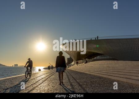 Lissabon, Portugal - 2018, 14.. Mai - Touristen laufen vor dem MAAT Museum während des Sonnenuntergangs in Lissabon Stockfoto