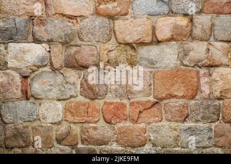 Eine alte Mauer aus Kopfsteinpflaster und großen Steinen in verschiedenen Formen und Farben Stockfoto