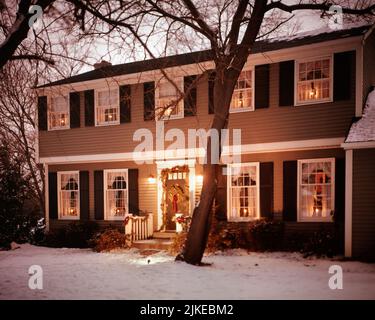 1970S ZWEISTÖCKIGE HAUS KERZENLICHTER IN JEDEM FENSTERKRANZ UND KIEFERNGIRLANDE VOR DER TÜR WEIHNACHTSDEKORATIONEN - KX8791 HAR001 HARS AUFREGUNG AUSSEN STOLZ HÄUSER DEZEMBER 25 RESIDENZ STILVOLL FRÖHLICH FESTLICH HAR001 ALTMODISCH Stockfoto