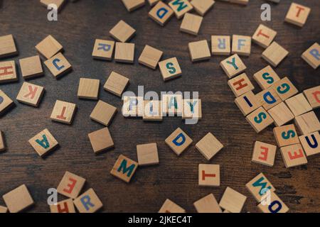 Lustige Idee für einen Spielabend mit Freunden. Bunte Holzbuchstaben von oben gesehen, die das WORTSPIEL schaffen. Freizeitaktivitäten. Hochwertige Fotos Stockfoto