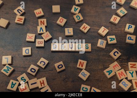 Das gefährliche Konzept des Drogenmissbrauchs, dargestellt durch symbolische Worträtsel, die das Wort DROGEN aus quadratischen Holzbuchstaben in den Blautönen erschaffen. Hochwertige Fotos Stockfoto