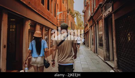 Ein paar Freunde laufen durch Venedig. Touristen in Italien gehen entlang einer schmalen Straße Stockfoto