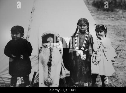 Historisches Schwarz-Weiß-Foto von vier Kindern der Südlichen Ute vor einem Tipi. Colorado. Stockfoto