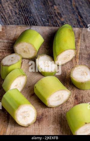 Unreife grüne Banane in Stücke geschnitten, Banane mit grüner Schale während des Kochens auf dem Tisch Stockfoto