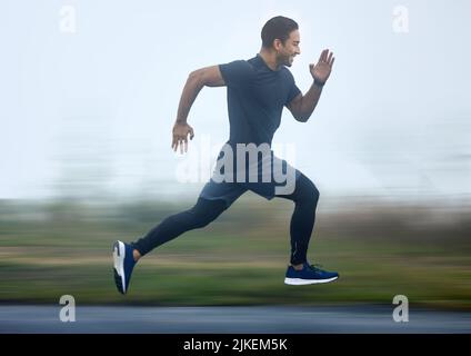 In jedem Schritt mit Geschwindigkeit boosting. Ein sportlicher junger Mann, der im Freien läuft. Stockfoto