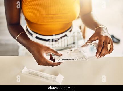 Nahaufnahme einer erwachsenen Frau, die ein Testkit mit Covid auspacken soll. Frau, die zu Hause einen Impfstoff für Corona-Tests auf Viren vorbereitet. Lady immer bereit, sich selbst Stockfoto