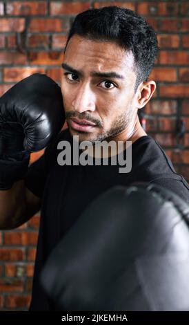 Fordern Sie sich jeden Tag der Woche heraus. Nahaufnahme eines jungen Mannes mit Boxhandschuhen. Stockfoto