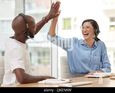 Sie haben gute Arbeit geleistet, Gut gemacht. zwei Callcenter-Mitarbeiter haben sich gegenseitig eine hohe fünf gegeben. Stockfoto