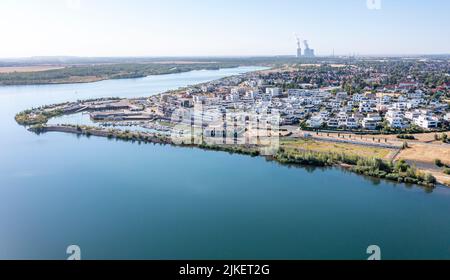 Zwenkau, Deutschland. 19.. Juli 2022. Am Kap Zwenkau am gleichnamigen See (Kraftwerk Lippendorf im Hintergrund) wurden ein Hafen und neue Wohngebäude errichtet. Aus dem ehemaligen Braunkohlebergwerk Zwenkau ist mit einer Fläche von knapp 10 Quadratkilometern der größte See der Region Leipzig hervorgegossen worden. Seit 2011 wird an der Zwenkau-Küste ein komplett neues Quartier errichtet, das Raum für Wohnen und Arbeiten bieten soll. (Luftaufnahme mit Drohne) Quelle: Jan Woitas/dpa/ZB/dpa/Alamy Live News Stockfoto